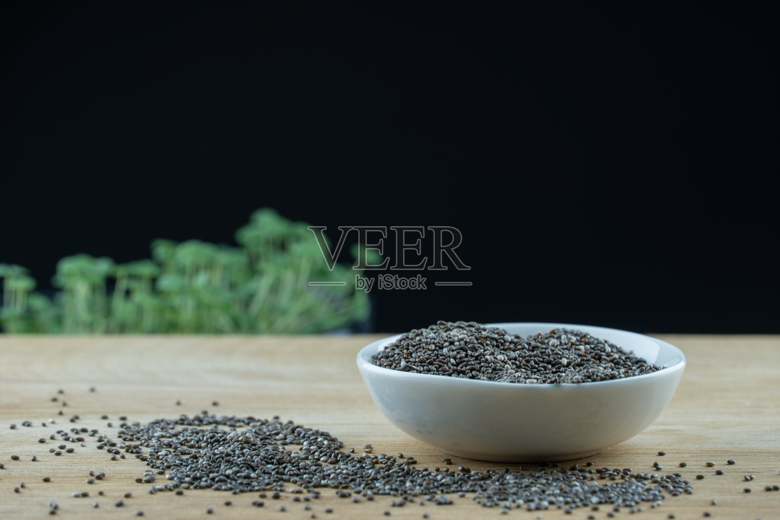 静物黑色种子奇亚在白色盘子上的木平台。照片摄影图片