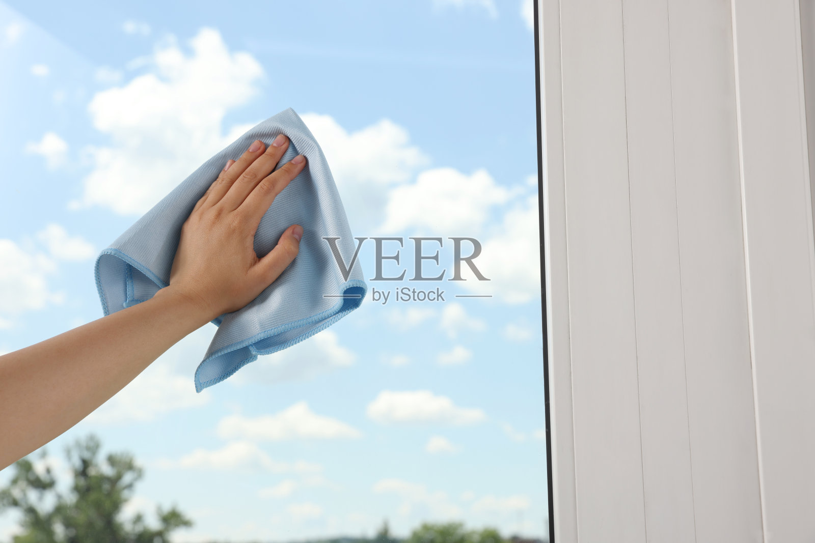 女人用抹布清洁室内窗户玻璃，特写照片摄影图片