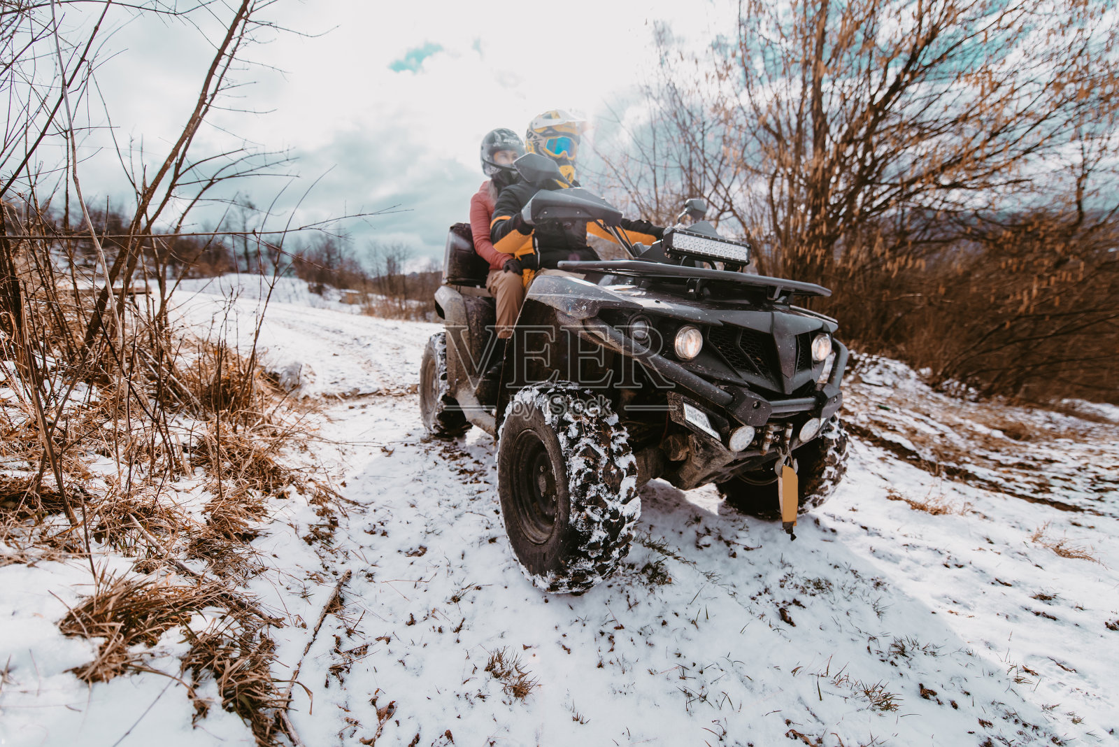 冬天的时候，人们在山顶上骑着四驱车享受着乐趣照片摄影图片
