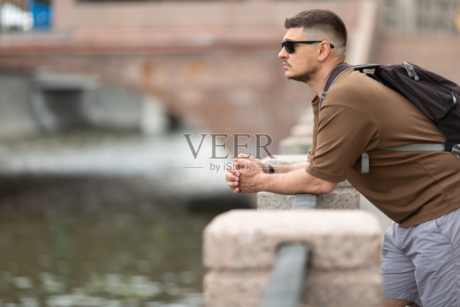 男人靠在堤岸栏杆上，若有所思地看着照片摄影图片