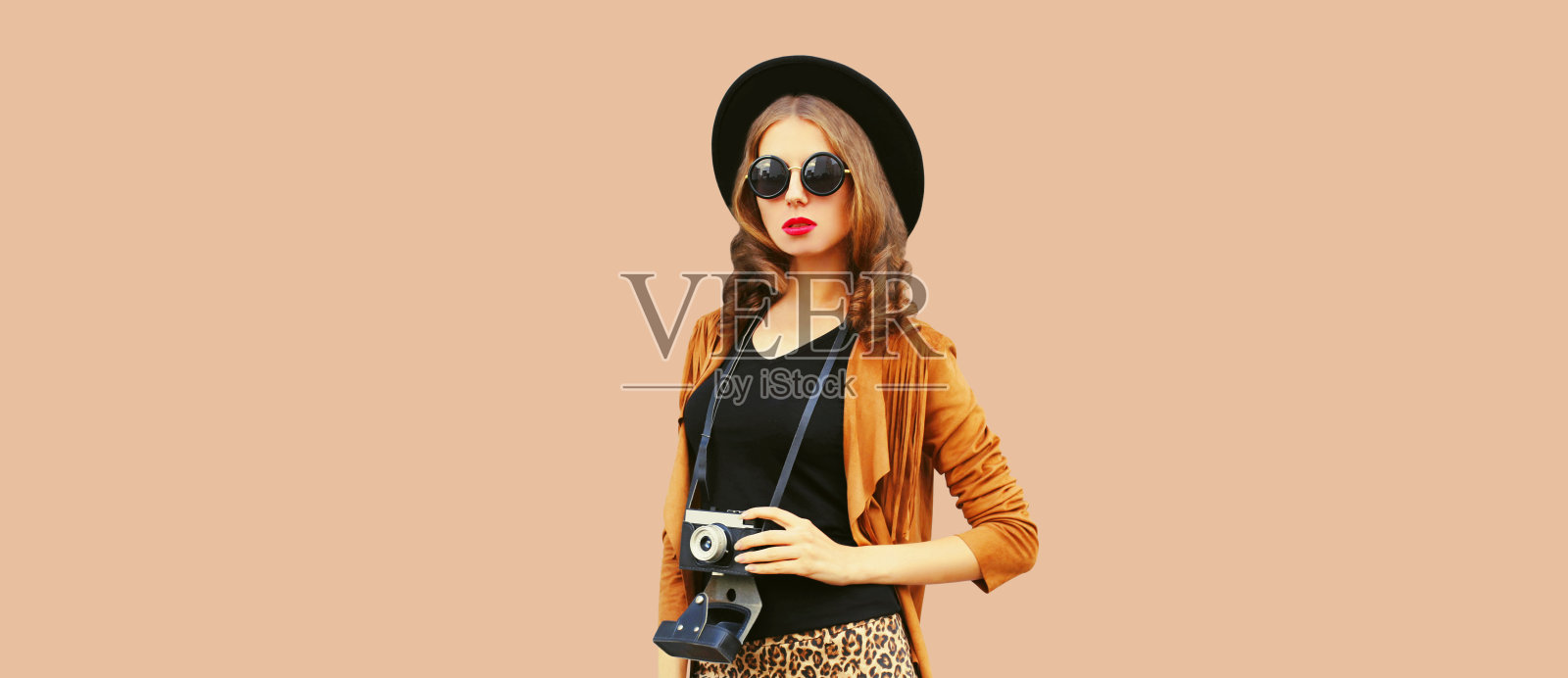 时尚的年轻女子摄影师的肖像与电影相机在棕色的背景照片摄影图片