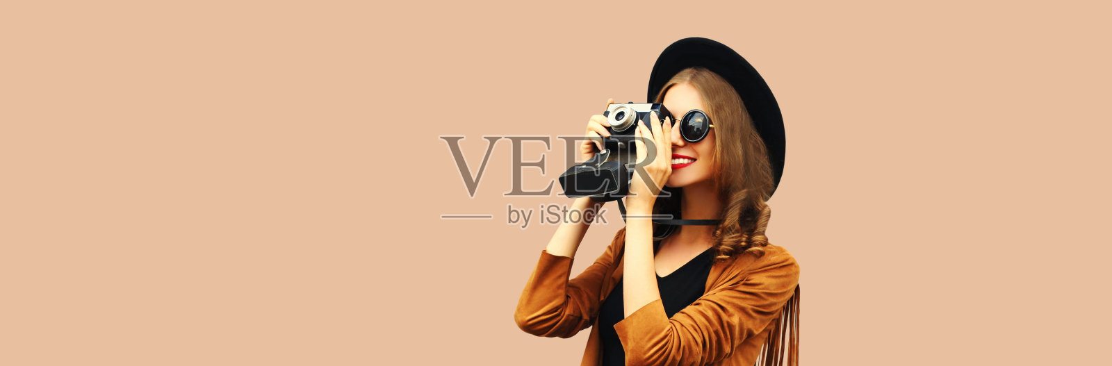 快乐微笑的年轻女子摄影师的肖像与胶卷相机在棕色的背景照片摄影图片