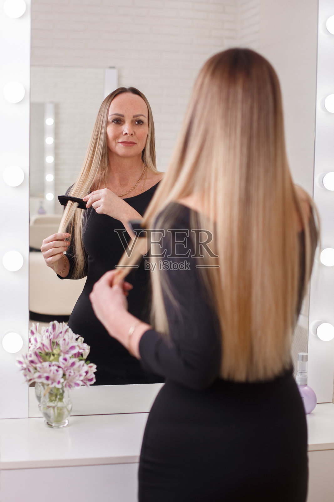 年轻的金发女人梳她的头发照片摄影图片