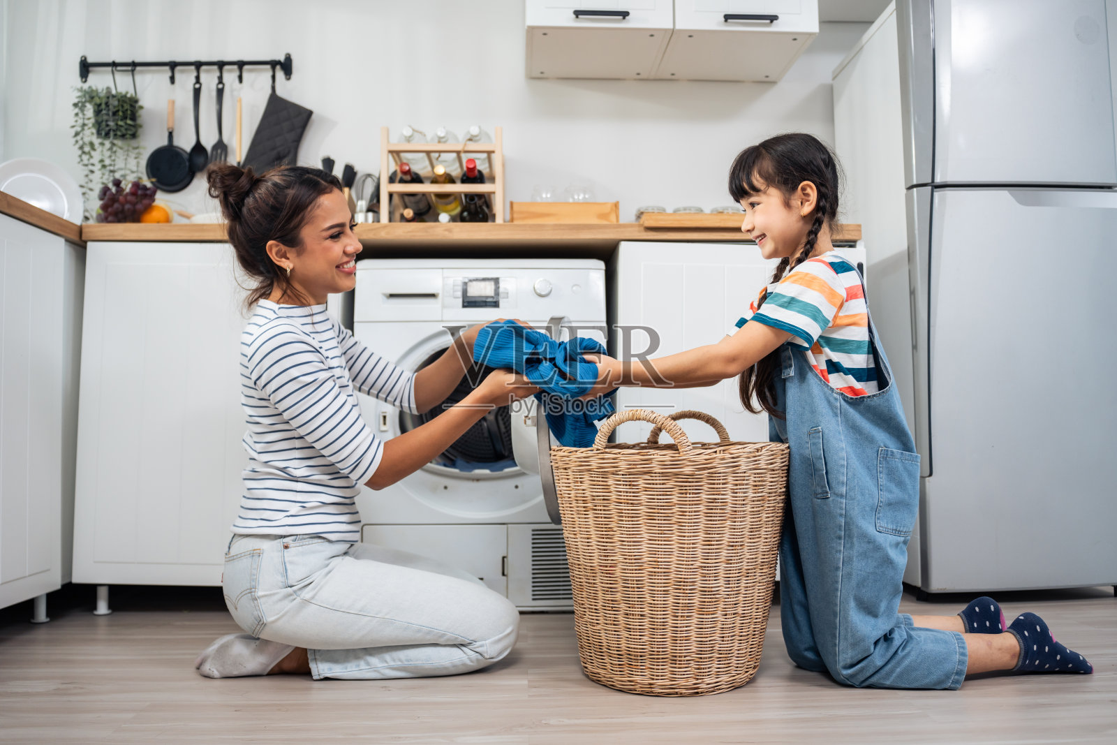白人美丽的母亲教年轻的女儿洗脏衣服。可爱的小可爱的女孩孩子帮助和学习父母妈妈把衣服放在洗衣机电器在家里。Domestic-Housekeeping。照片摄影图片