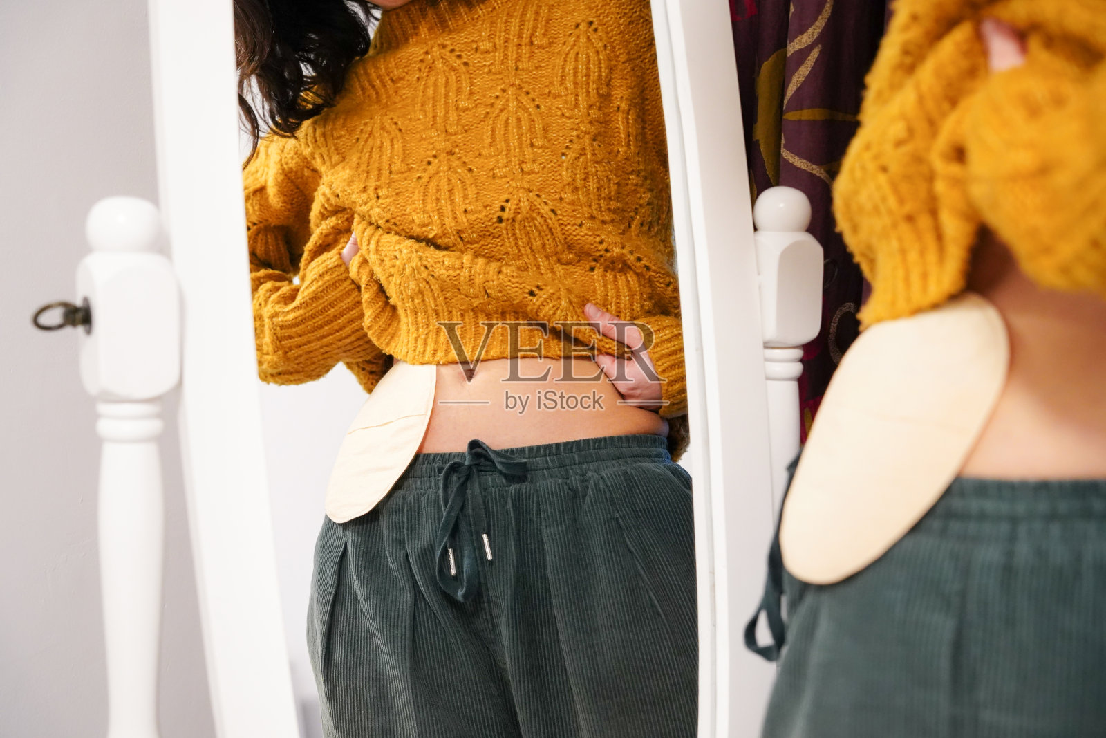 一个不认识的年轻女人看着镜子里的造口袋。消化系统癌症的优势照片摄影图片