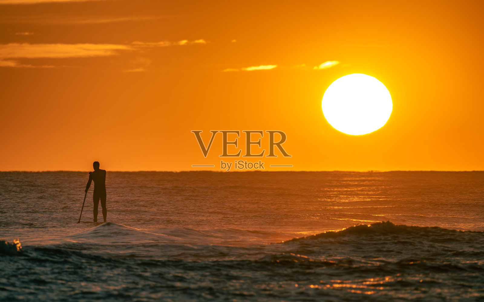 男子练习划桨冲浪在海上与日落照片摄影图片