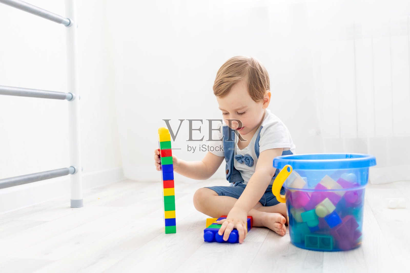 一个孩子在家里有一个构造器，一个可爱的男孩玩或收集一个彩色构造器照片摄影图片