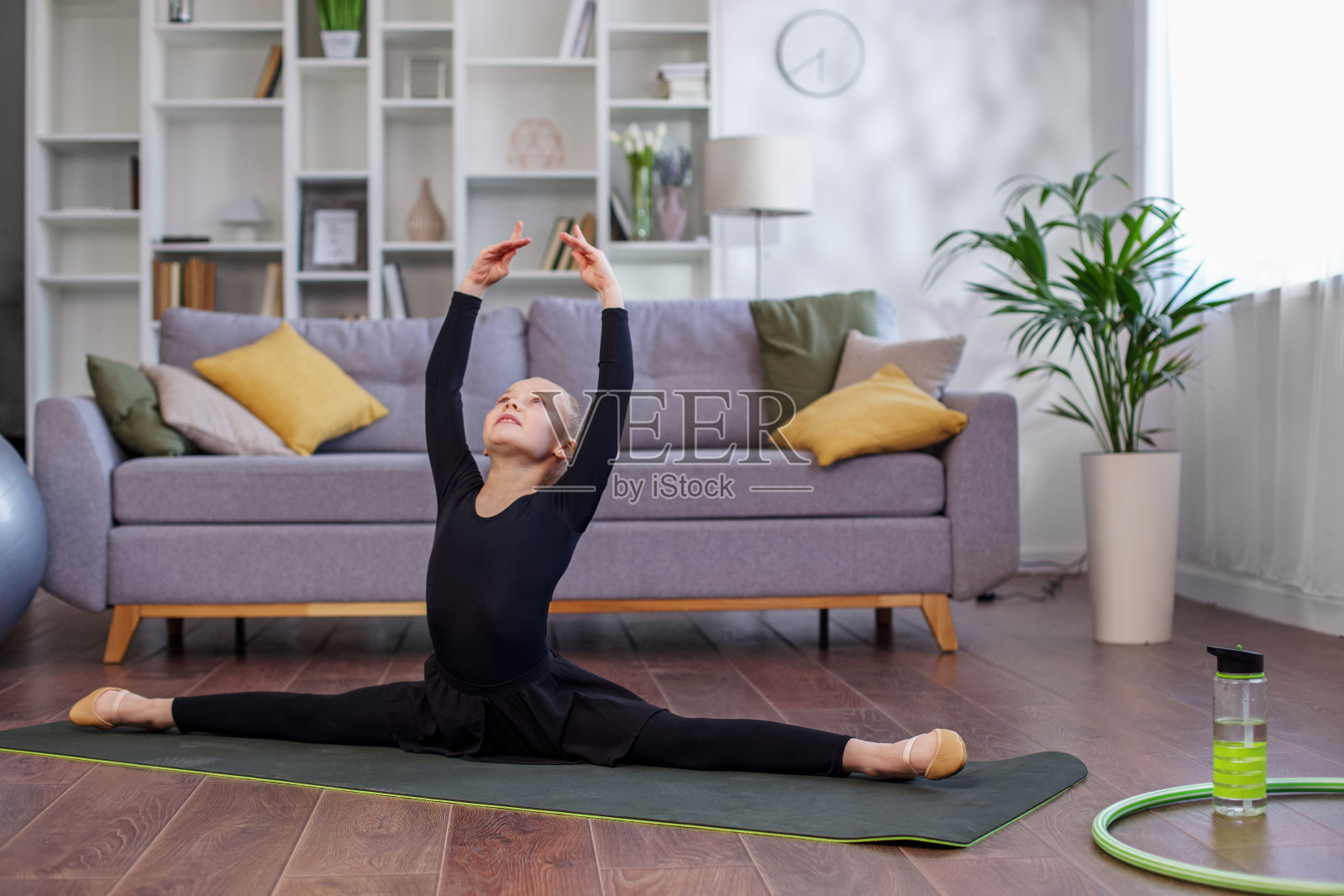 小女孩在房间里练习拉伸。儿童在家进行体育锻炼。体育的概念照片摄影图片