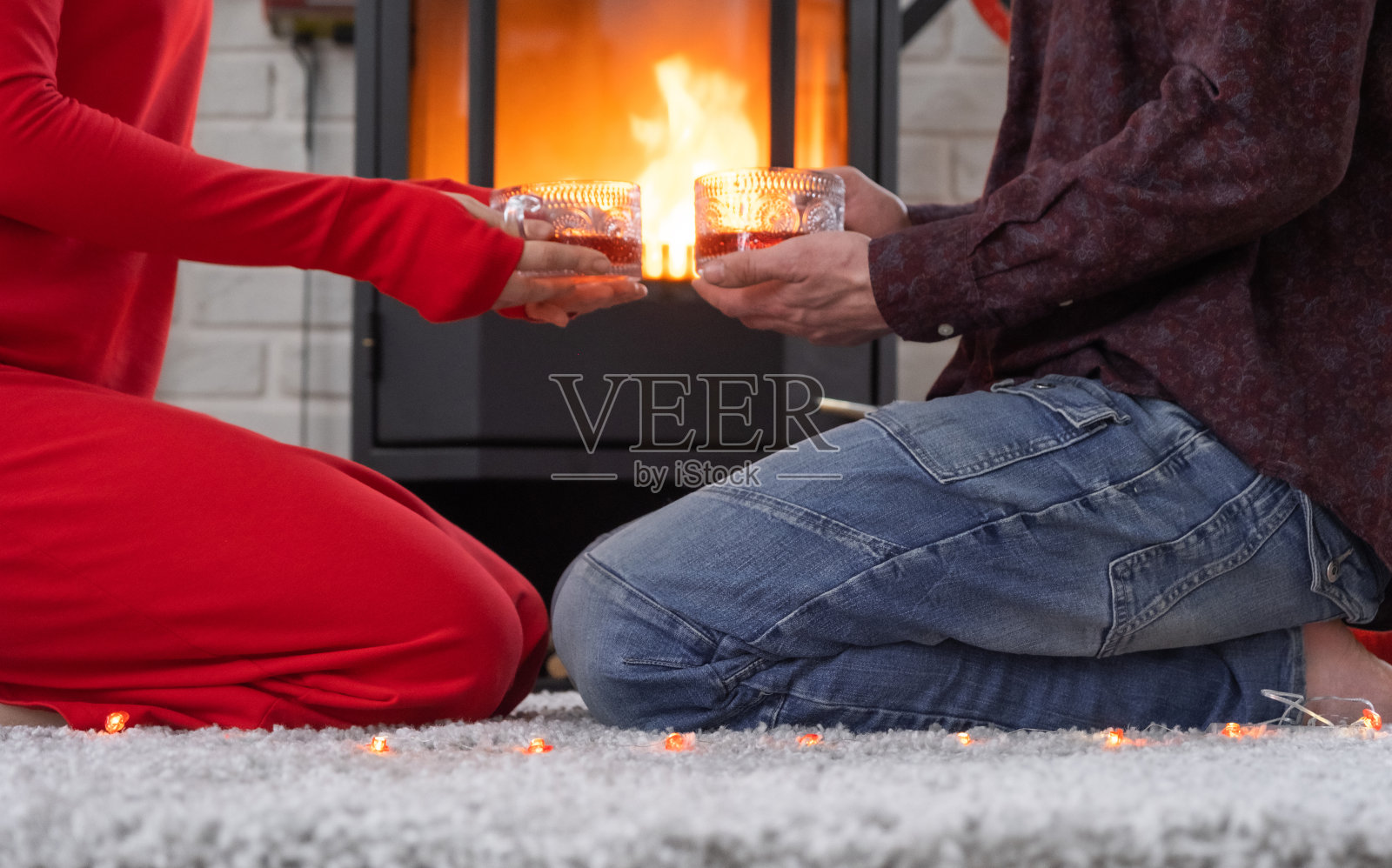 相爱的男女在家里约会，坐在火炉旁，舒适的地毯上燃烧着火焰。情人节，幸福的情侣，爱情故事，人际关系照片摄影图片