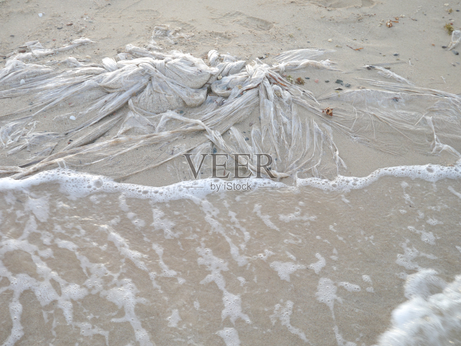 海滩上的塑料包装膜与海洋污染照片摄影图片