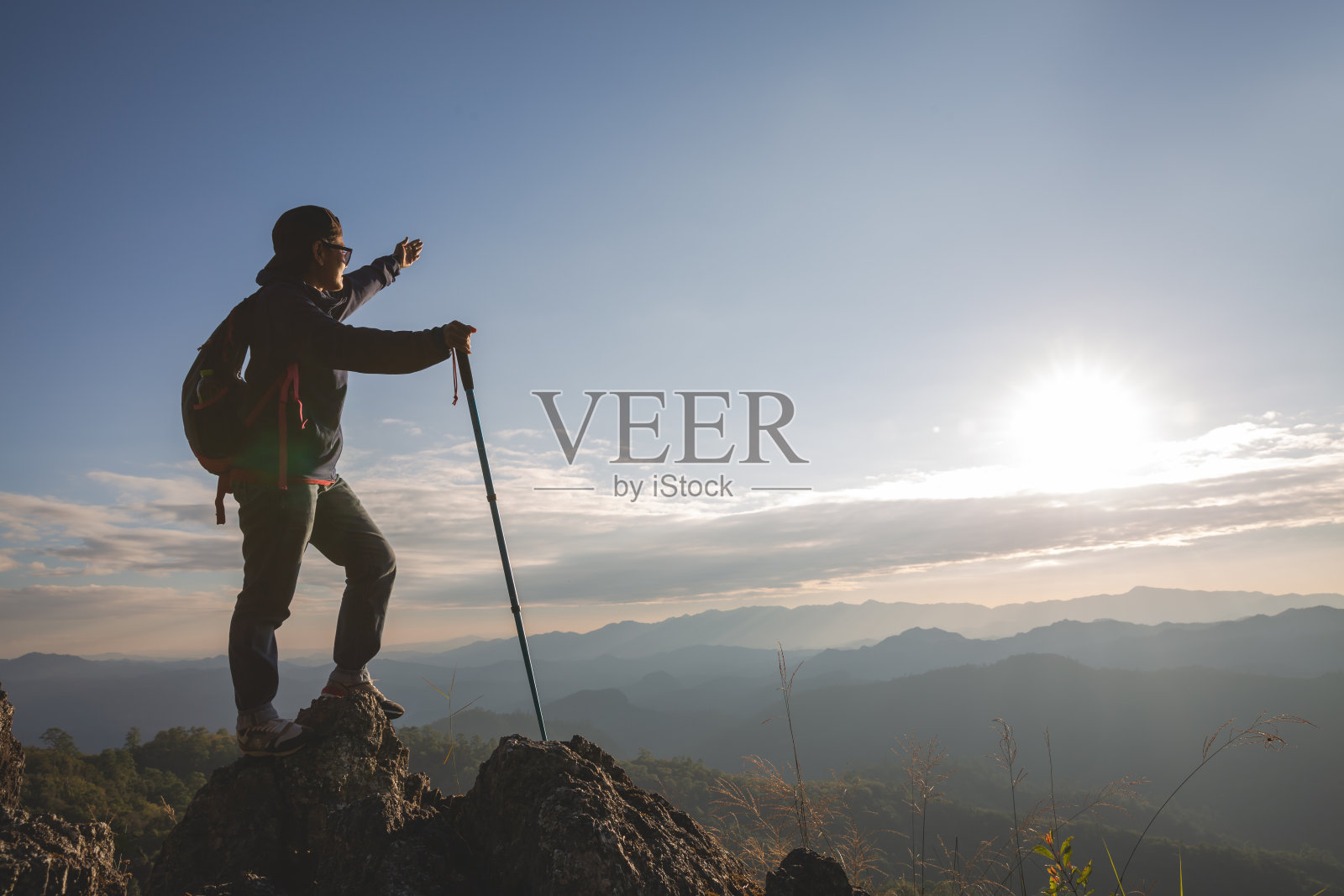 年轻人背着背包，拿着望远镜坐在山顶上，徒步旅行的概念照片摄影图片