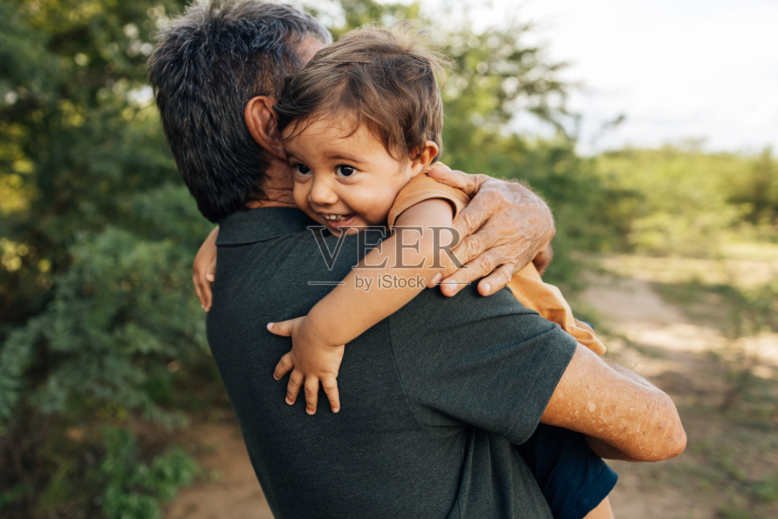 阳光明媚的日子里，顽皮的爷爷和孙子在公园里玩耍照片摄影图片