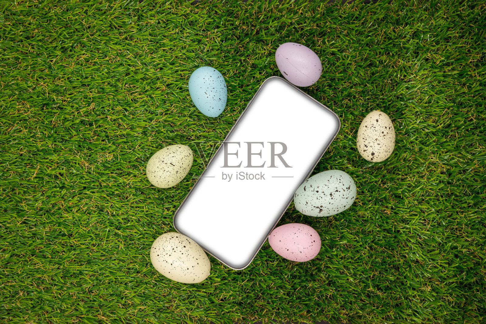 手机与空白空屏幕的背景上的复活节彩蛋与在绿色的草地。文本空格。复活节快乐!智能手机模型，俯视图照片摄影图片