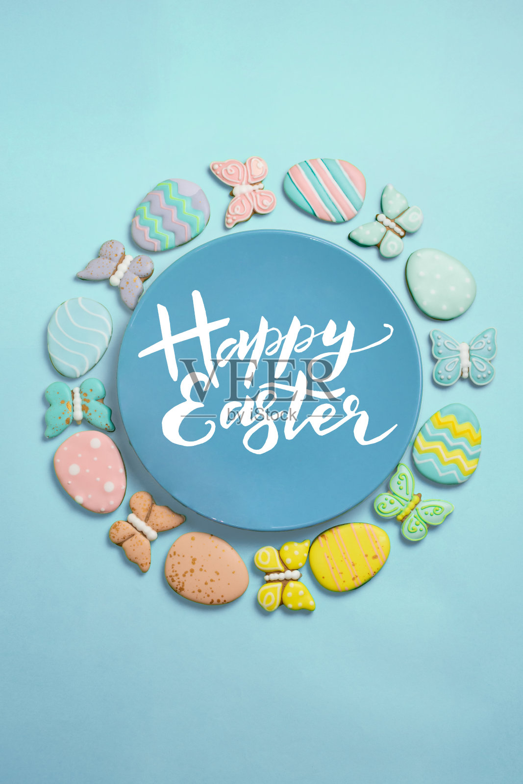 蓝色背景上的复活节横幅。自制的姜饼饼干放在蓝色的盘子里，复活节彩蛋和兔子和蝴蝶形状的饼干。复活节的概念。照片摄影图片