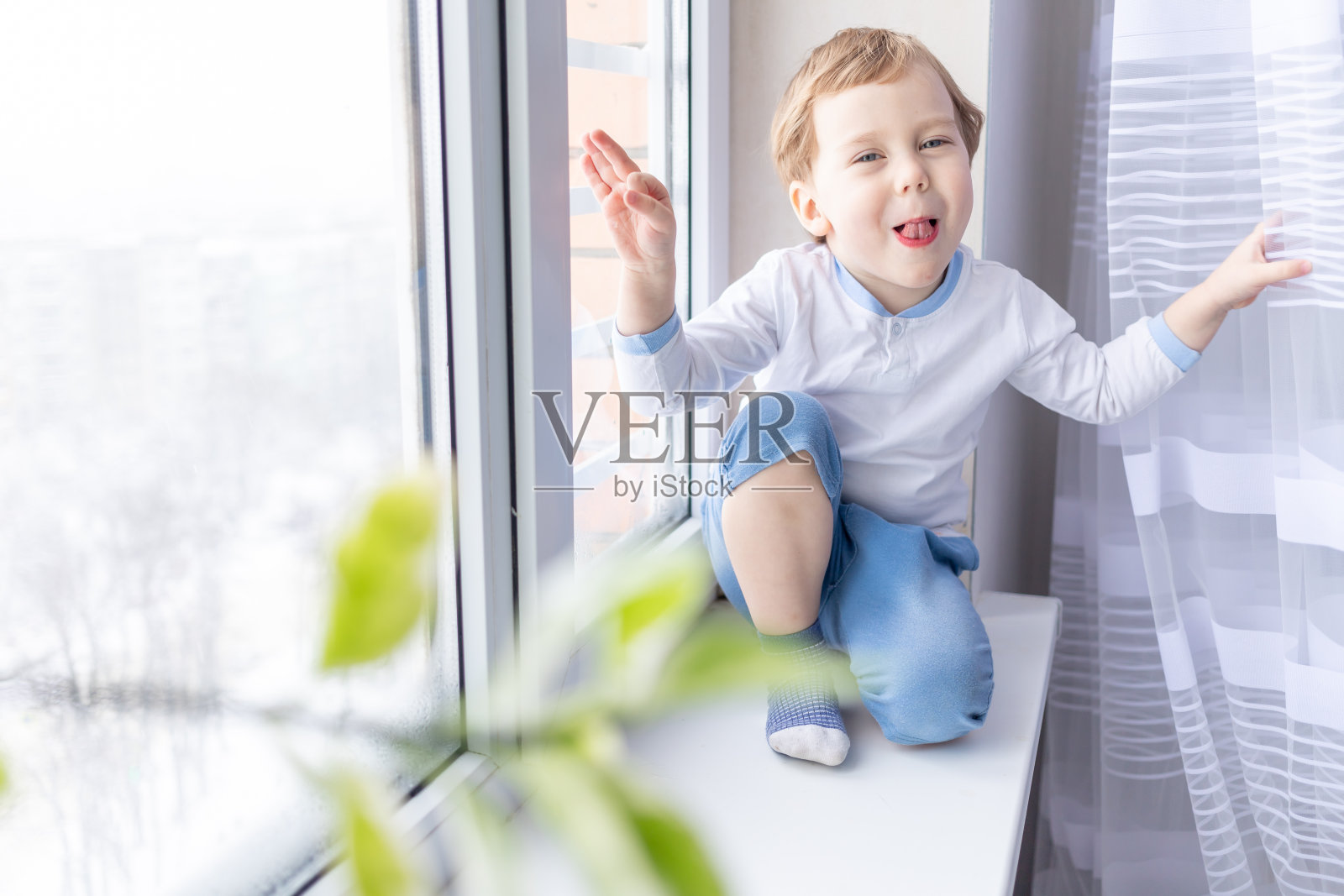 一个小男孩坐在房子的窗台上向窗外望去照片摄影图片