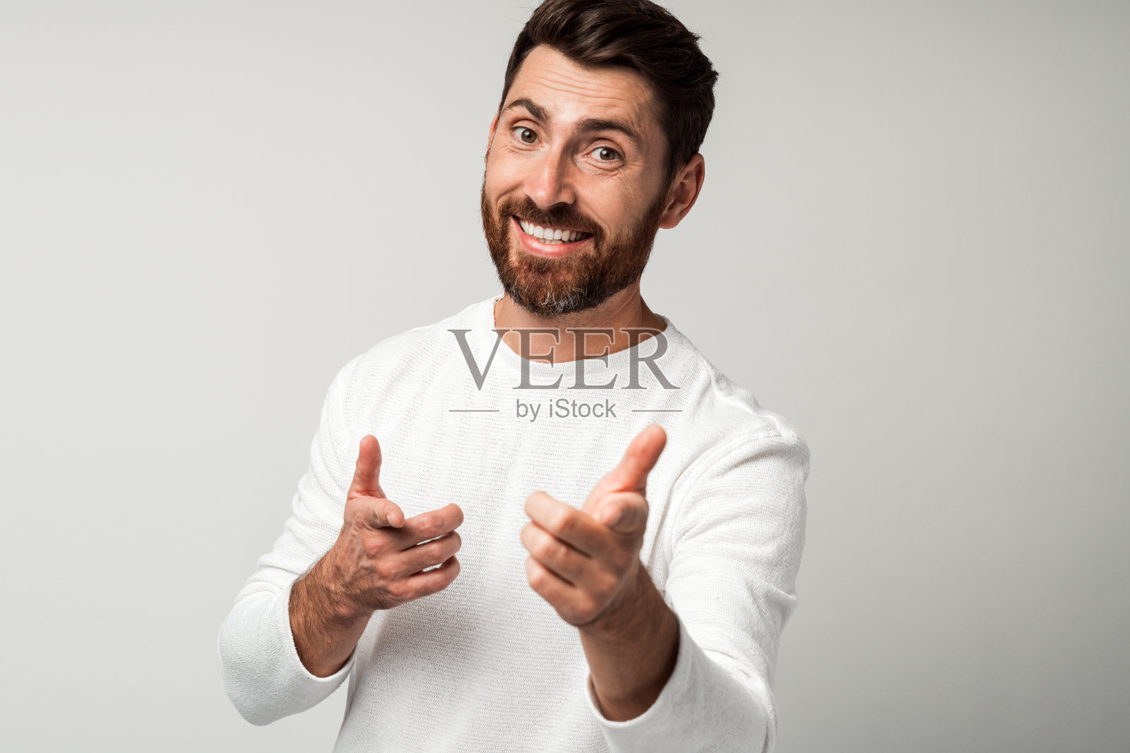 穿着白衬衫的快乐大胡子男人用手指指着某人照片摄影图片