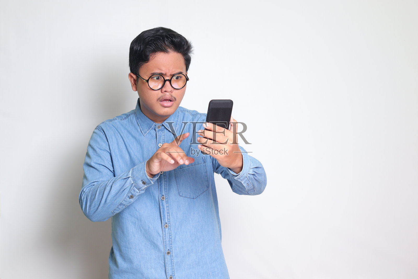 亚洲男人在看手机。哇脸表情照片摄影图片