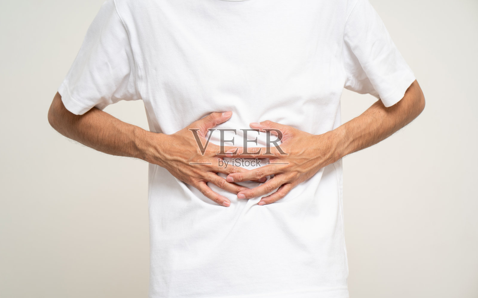 这名男子患有胃痛和胃炎。他把手放在自己的肚子上，捏了捏来放松和安抚他上厕所需要拉屎的时候。在孤立的白色背景上拍摄。照片摄影图片