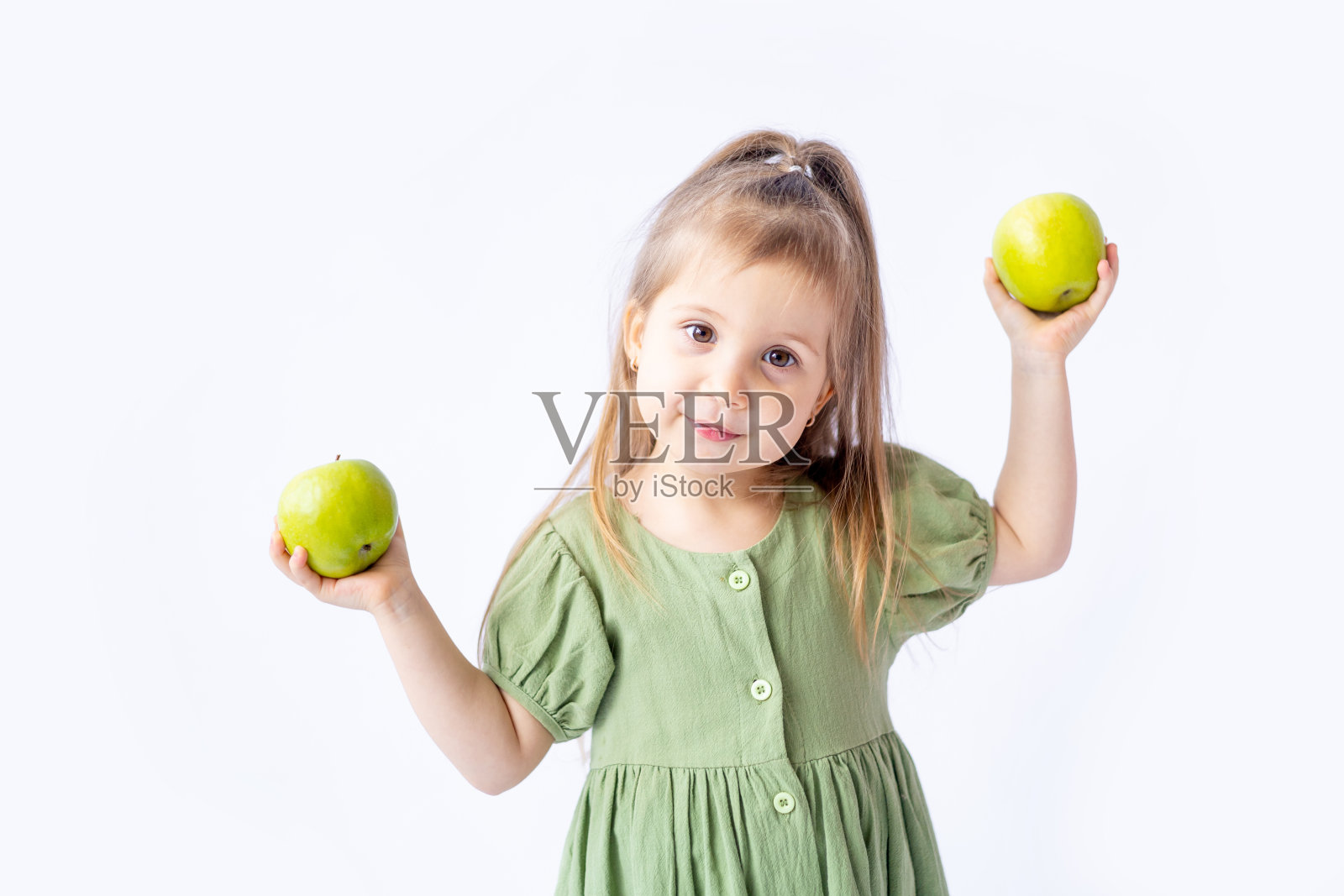 一个可爱的小女孩手里拿着一个大绿苹果。白色隔离背景。儿童健康食品或健康零食。文本空格。高质量的摄影照片摄影图片
