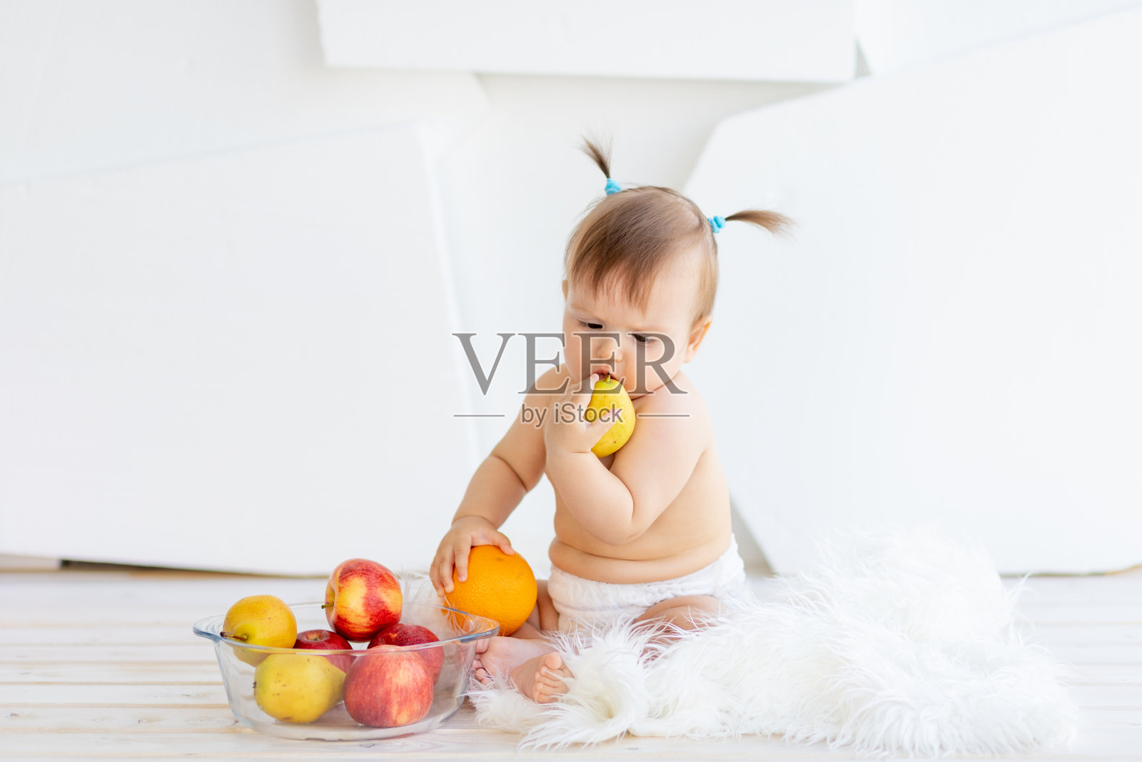 一个小女孩坐在明亮的房间里，手里拿着一盘水果照片摄影图片