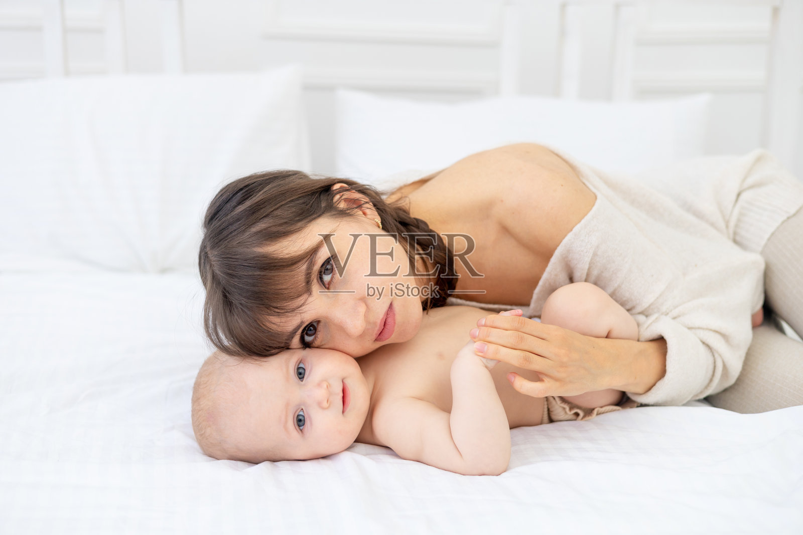 一个年轻的妈妈温柔地拥抱和亲吻一个六个月大的宝宝抱在怀里，爱，妈妈对宝宝的呵护，快乐的妈妈照片摄影图片