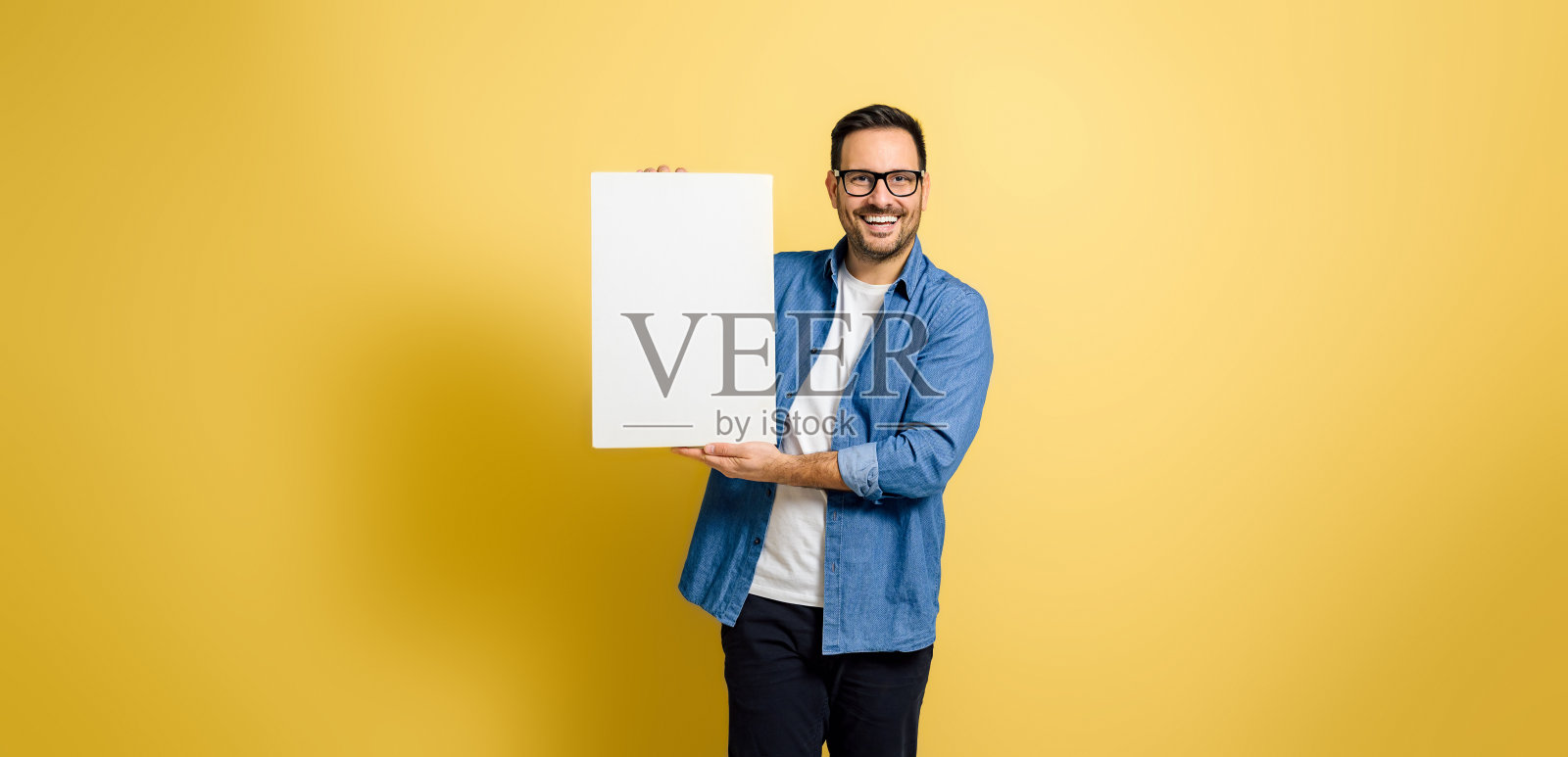 中年成人快乐的商人拿着空白的白色横幅模板模拟和微笑的镜头，而站在孤立的黄色背景照片摄影图片