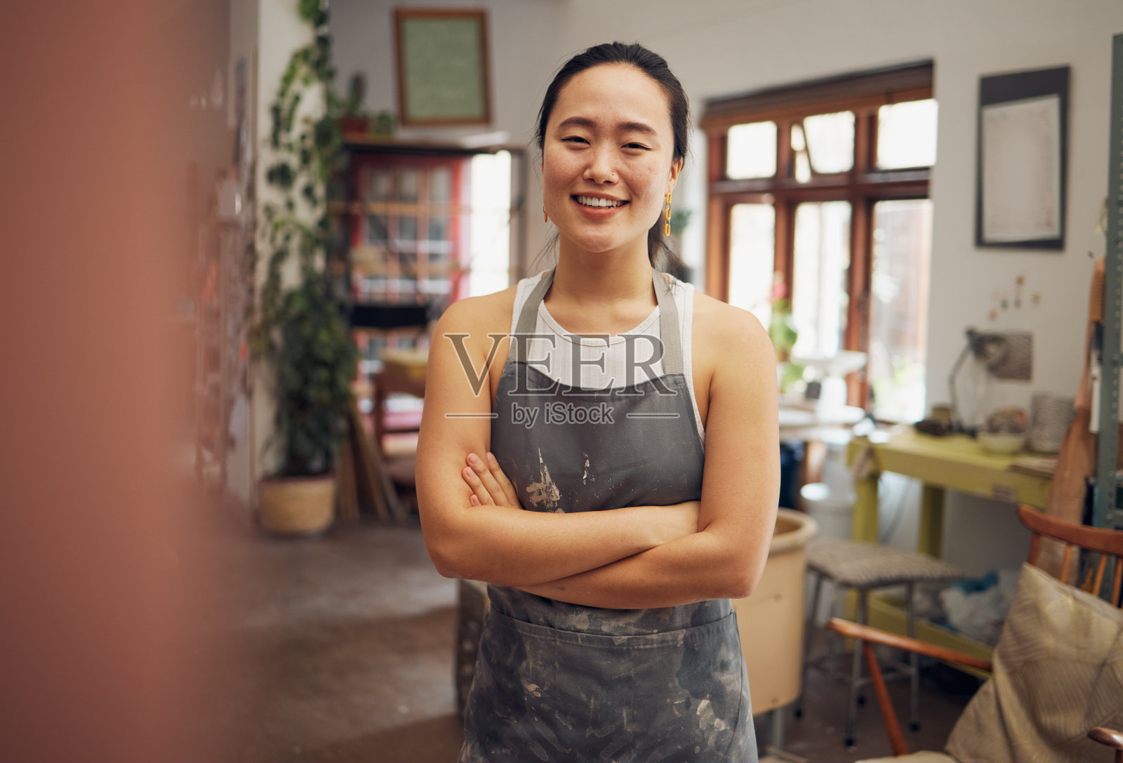 亚洲女性，陶工或双臂交叉的肖像在陶器工作室，小型企业或陶瓷作坊。微笑，快乐或粘土制品工人和信心，愿景或目标的创意商店设计照片摄影图片