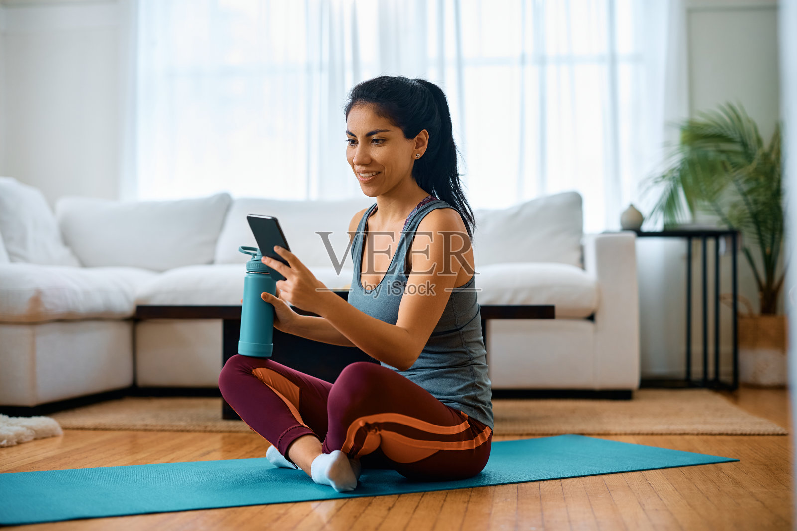 快乐的运动女性在手机上发短信，而在家里工作。照片摄影图片