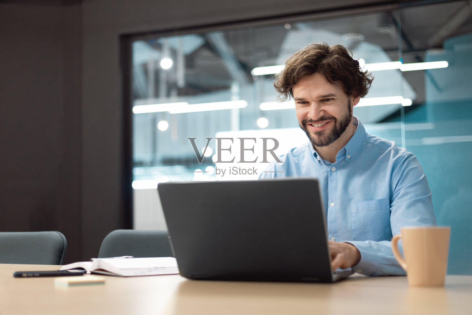 微笑的商人使用笔记本电脑坐在办公桌在办公室照片摄影图片