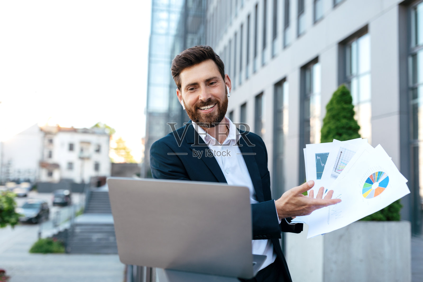 微笑自信的年轻白人男性胡须西装有视频通话与图表和笔记本电脑户外照片摄影图片