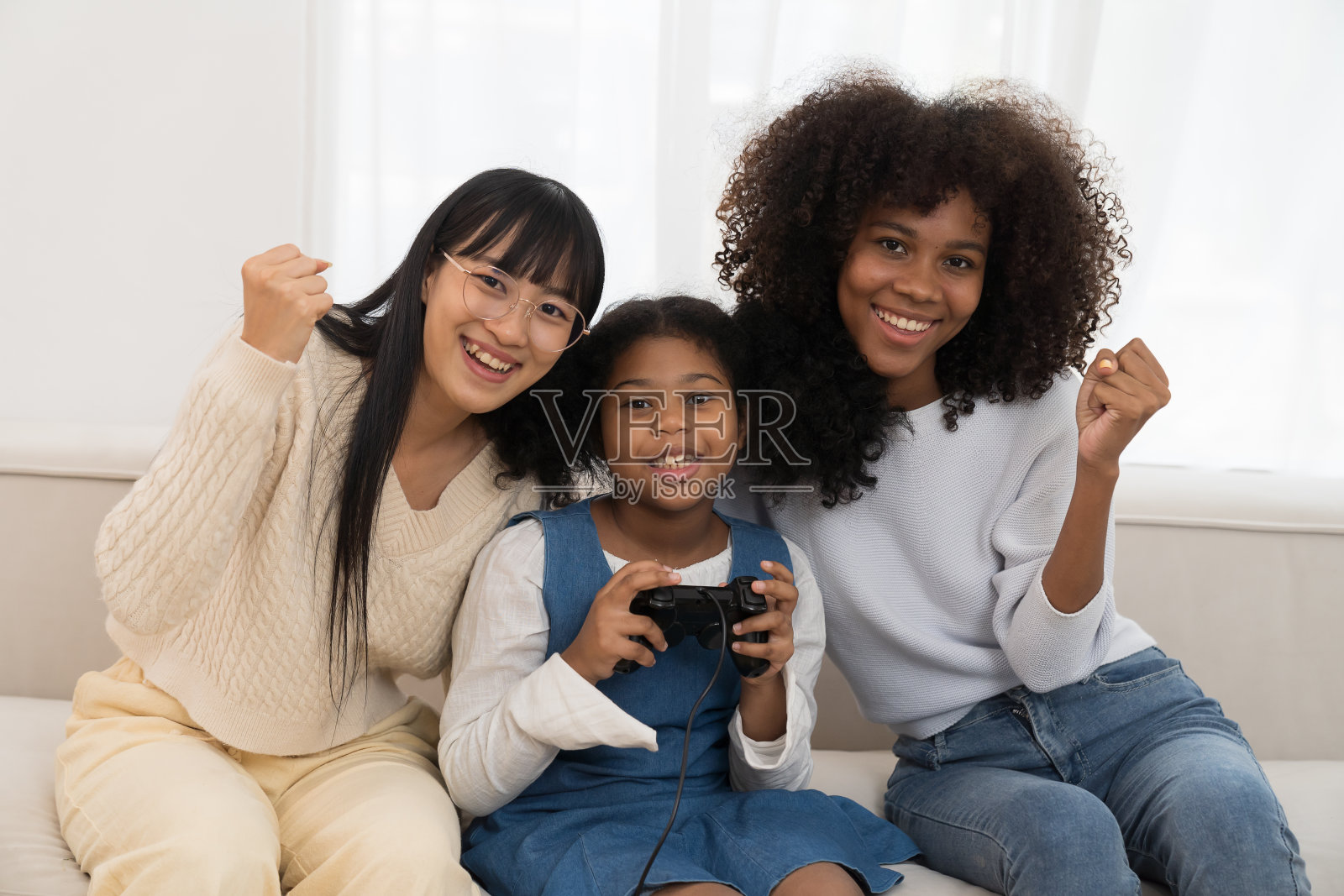 年轻女性和孩子周末一起在家玩电子游戏放松。快乐的亚洲妇女在家里的沙发上玩操纵杆游戏照片摄影图片