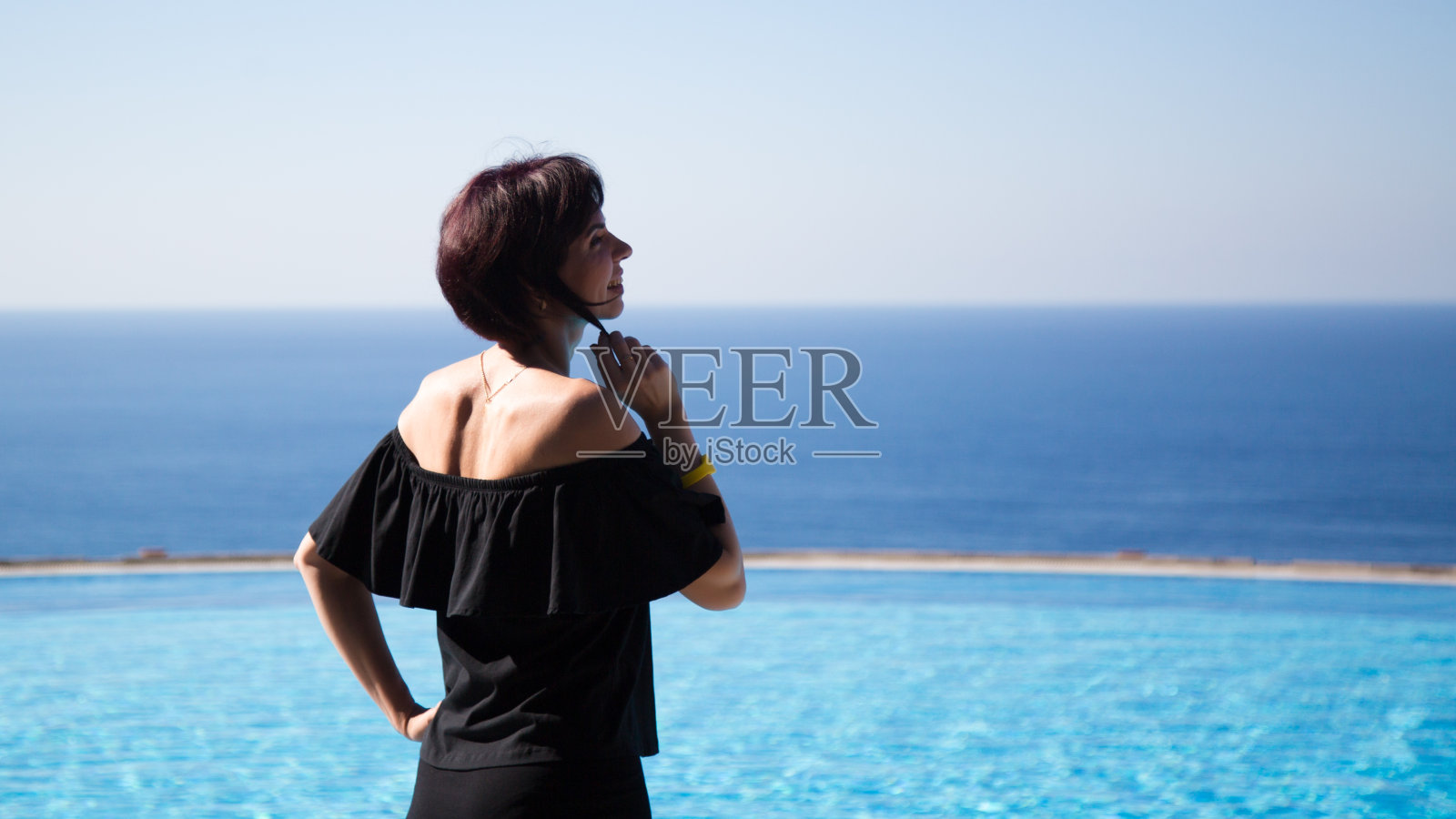 海边泳池边的女人抱着她的头发照片摄影图片