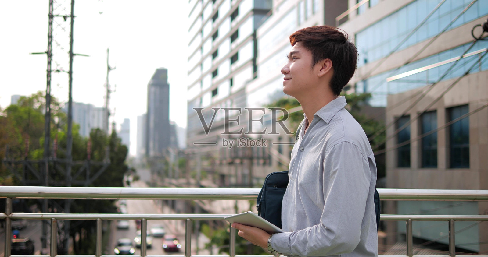 快乐的亚洲商人走在现代城市的街道上，户外有建筑背景照片摄影图片