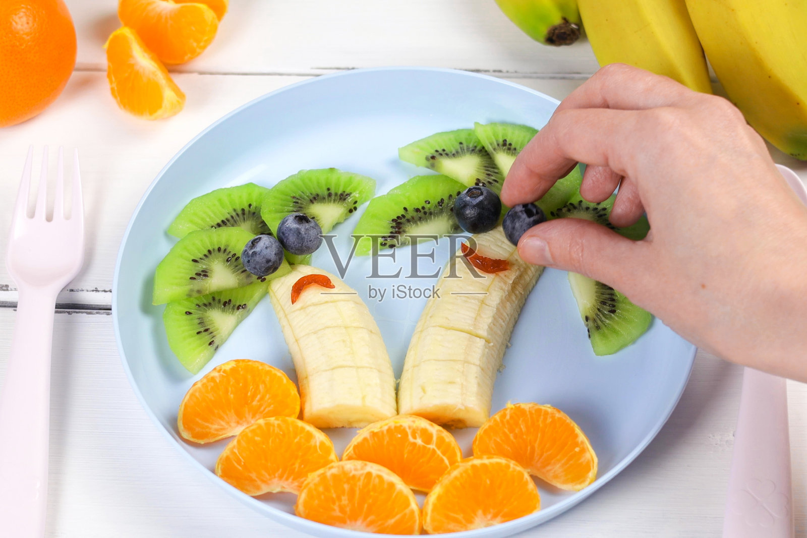 创意婴儿食品，猕猴桃，橘子，香蕉，彩色餐具上的有趣食物。给孩子的水果。俯视图，平面布局照片摄影图片