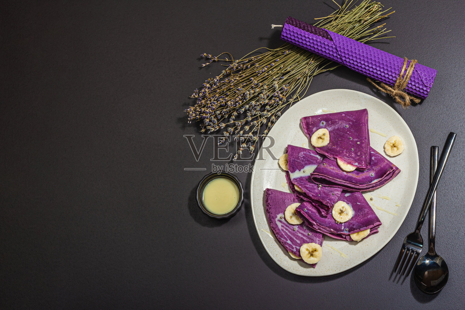 薰衣草薄煎饼配香蕉片和甜的浇头。健康的纯素无乳糖食品照片摄影图片