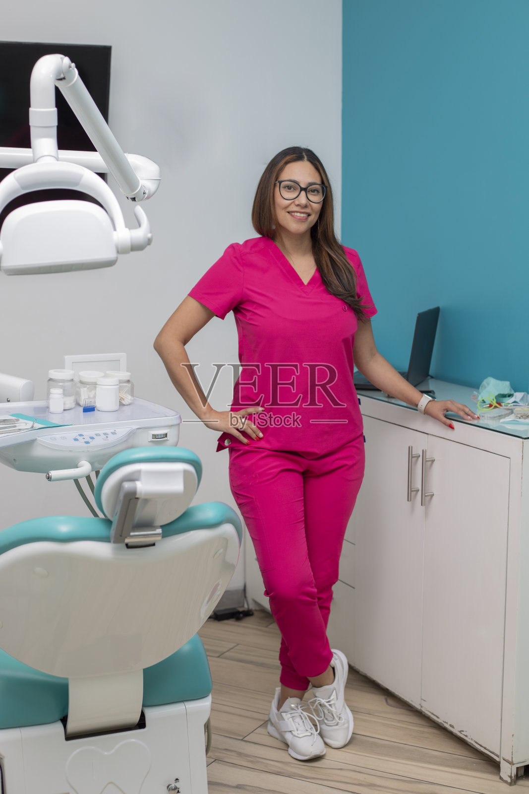 一位女牙医站在她的办公室里看着镜头照片摄影图片