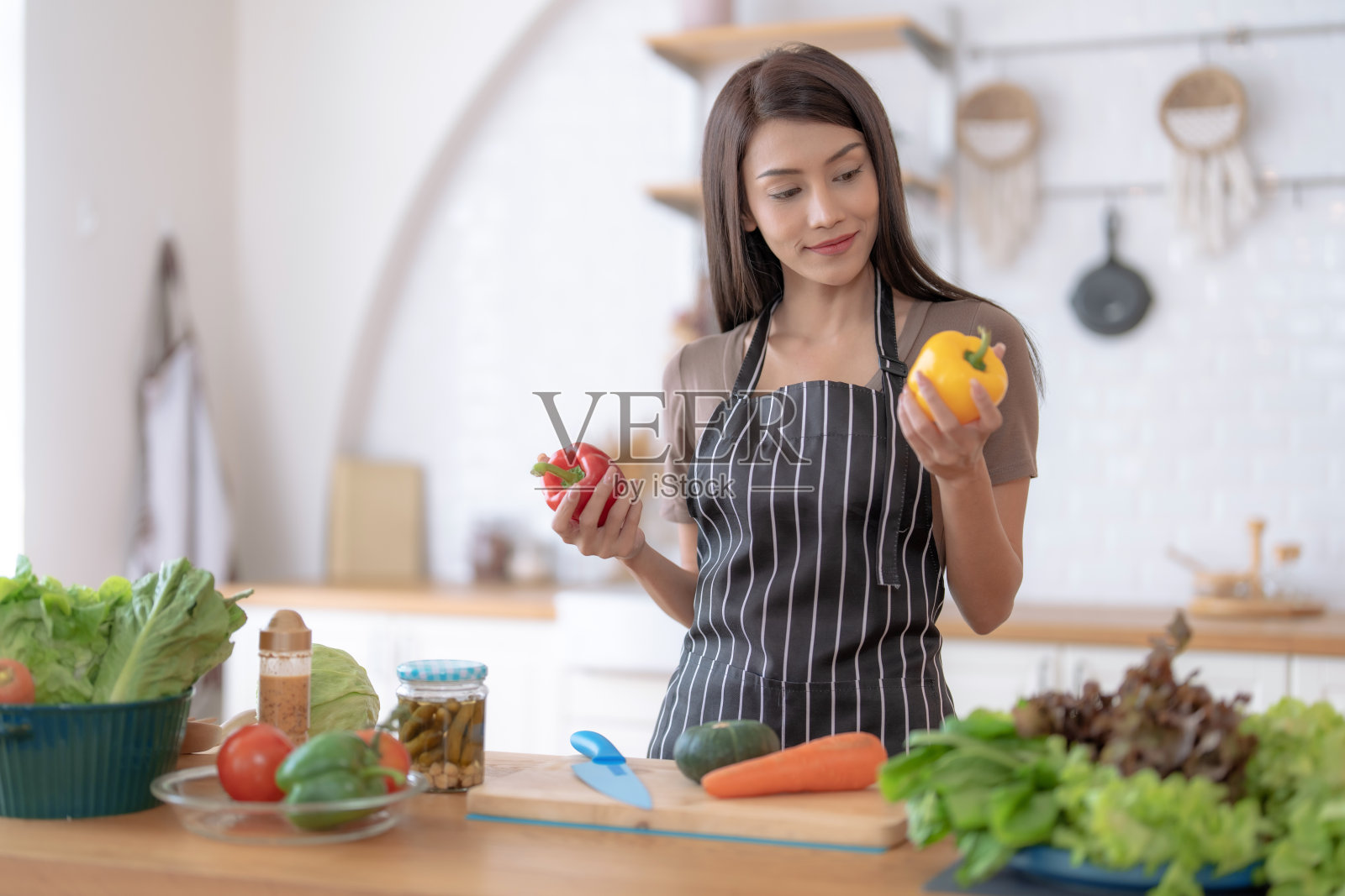 年轻的亚洲女人在家里的厨房做饭。照片摄影图片