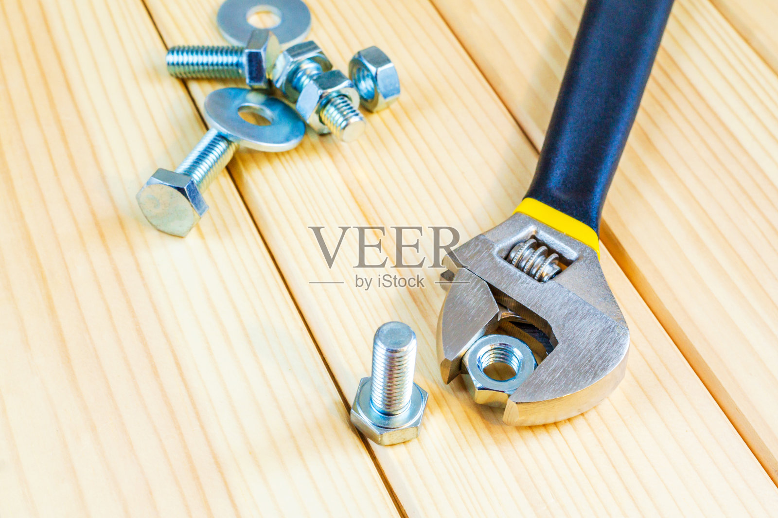 木制背景上的金属螺栓和螺母，带活动扳手照片摄影图片
