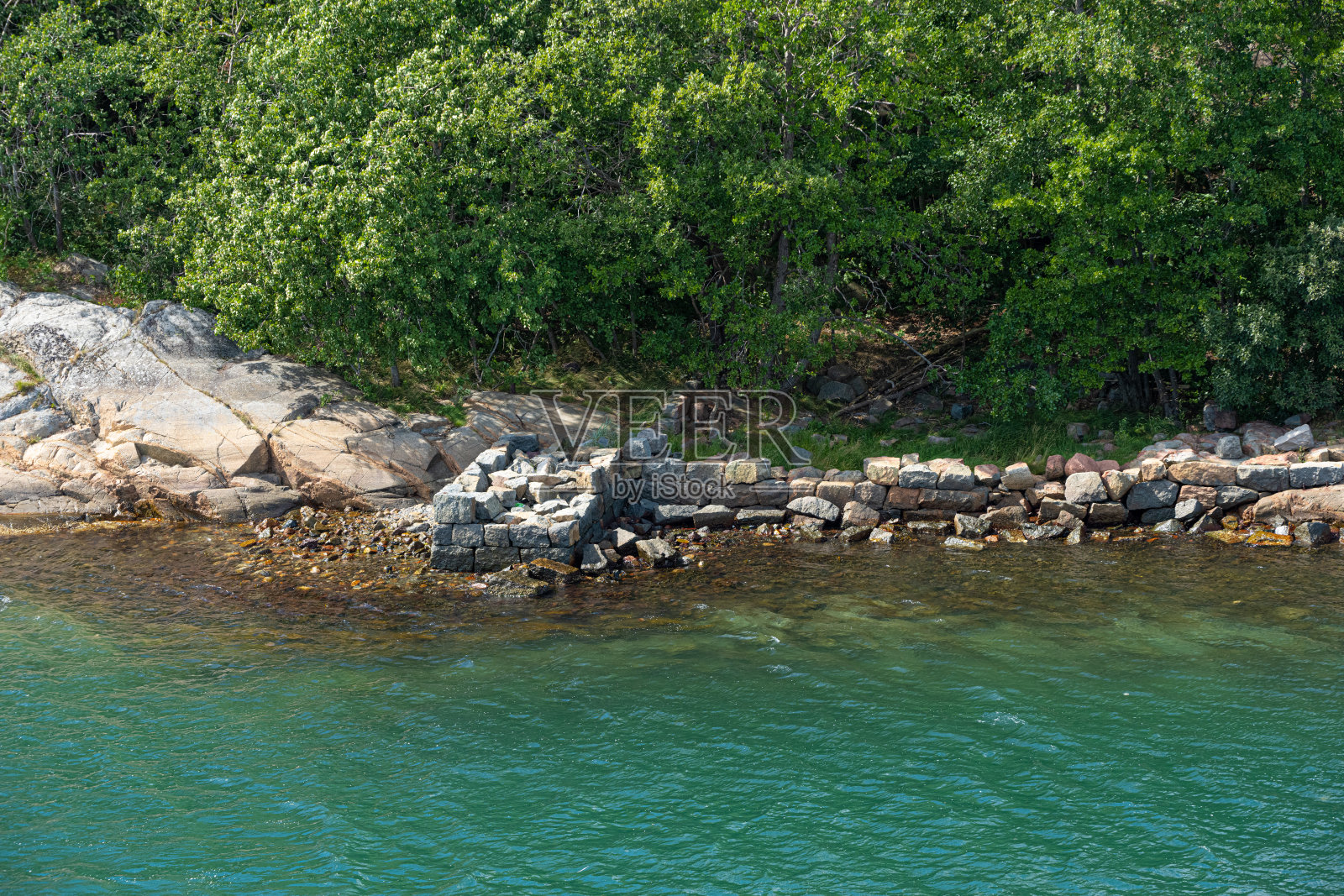 绿色峡湾边废弃的老石墩。照片摄影图片