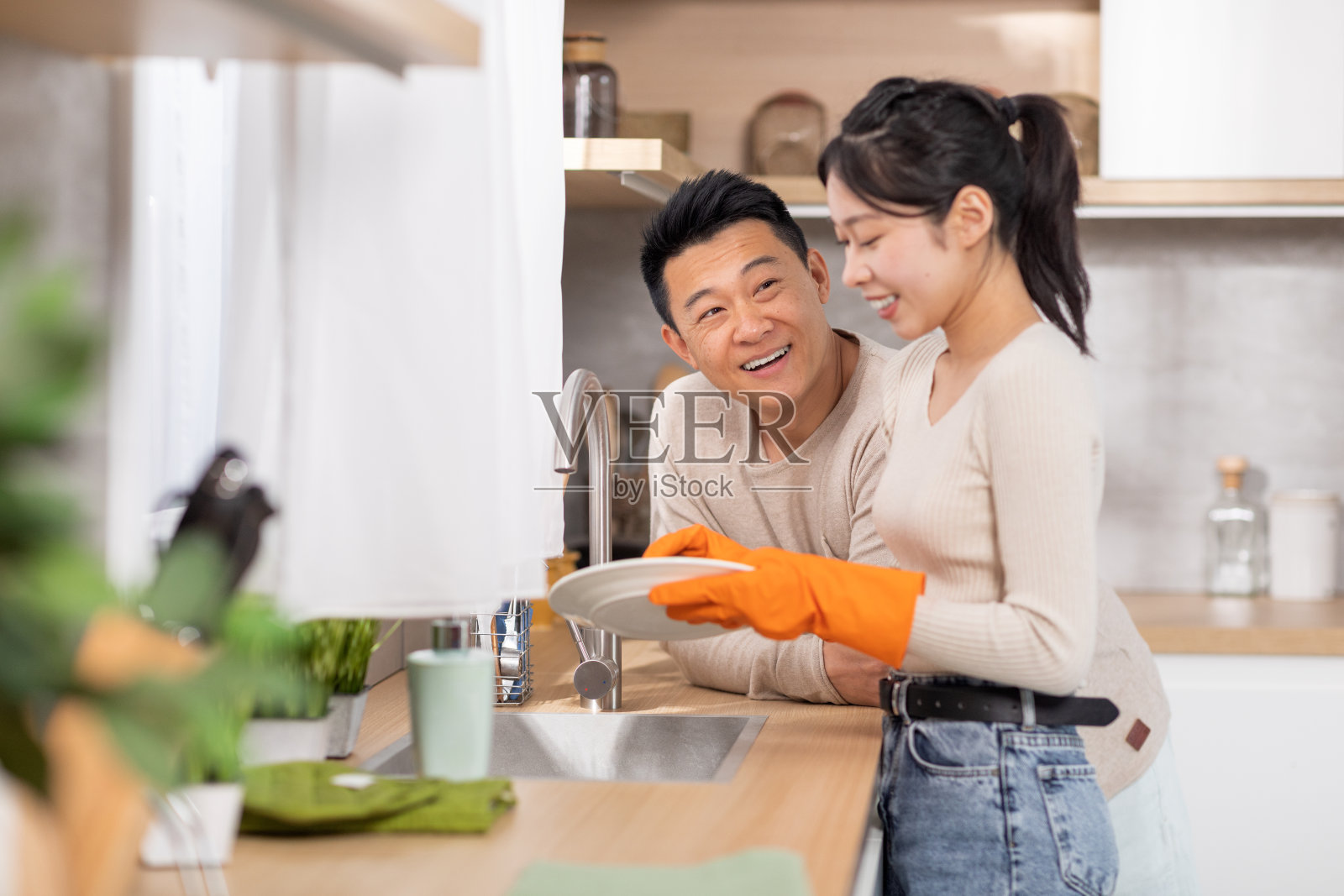 有爱的丈夫在妻子洗碗时扶着她照片摄影图片