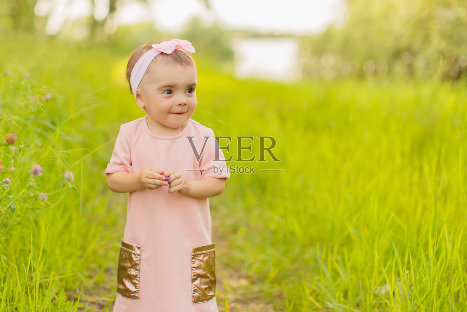 在春天自然的背景下，女孩穿着粉红色的连衣裙。绿色的草。照片摄影图片