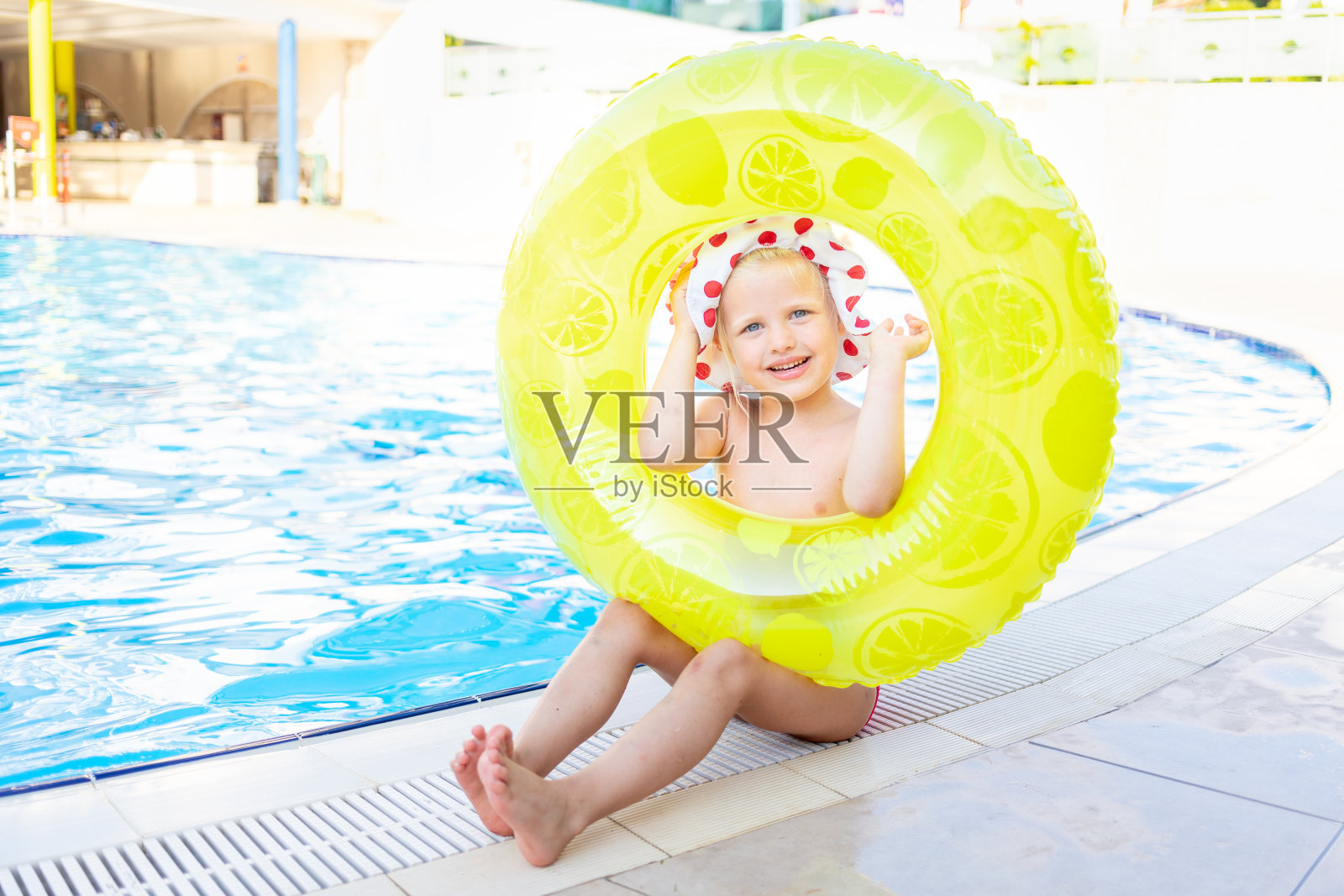 夏日泳池边的充气黄色圆圈里，快乐快乐的小宝贝望着窗外，微笑着，旅游休闲的概念照片摄影图片