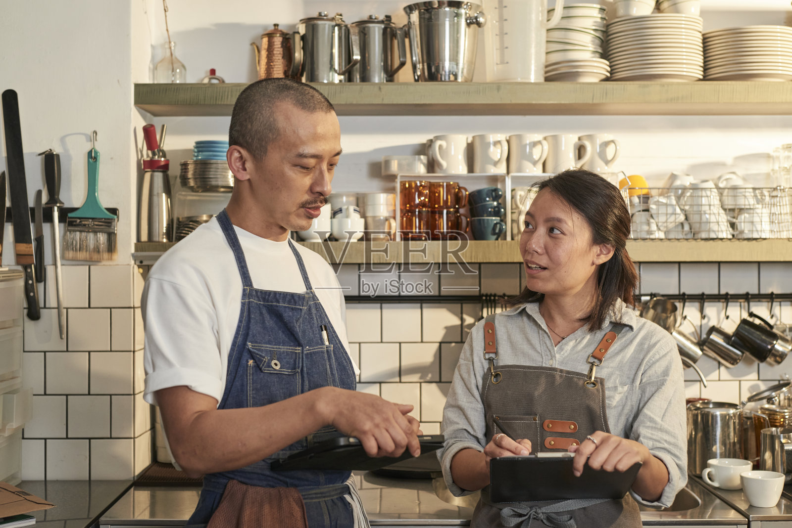年轻的咖啡师使用数码平板电脑在咖啡店处理网上订单。照片摄影图片