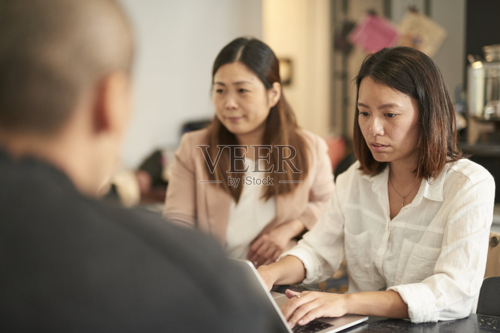 年轻的亚洲美女在咖啡店用平板电脑讨论业务问题。照片摄影图片