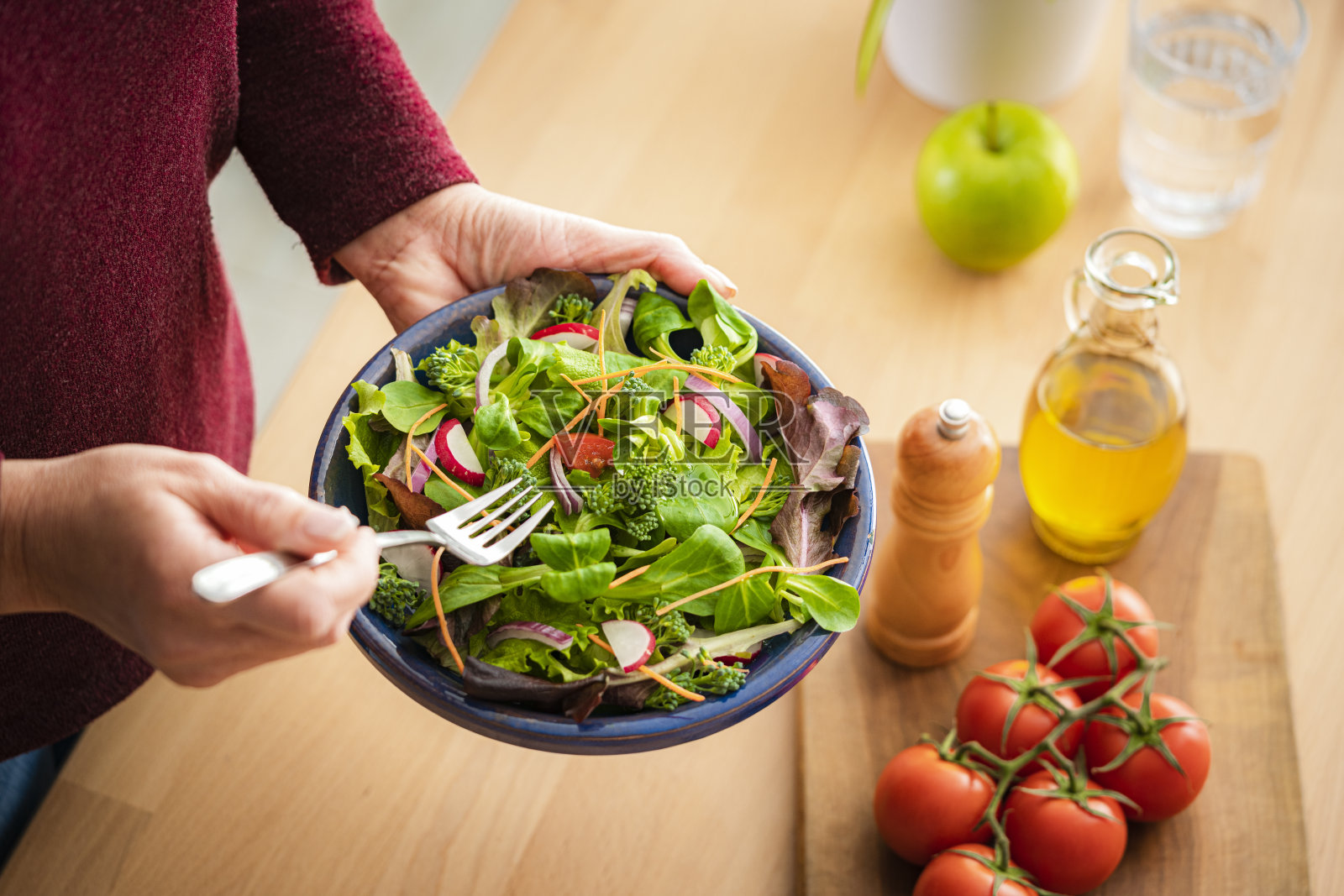 女人在木桌上吃新鲜的沙拉盘照片摄影图片