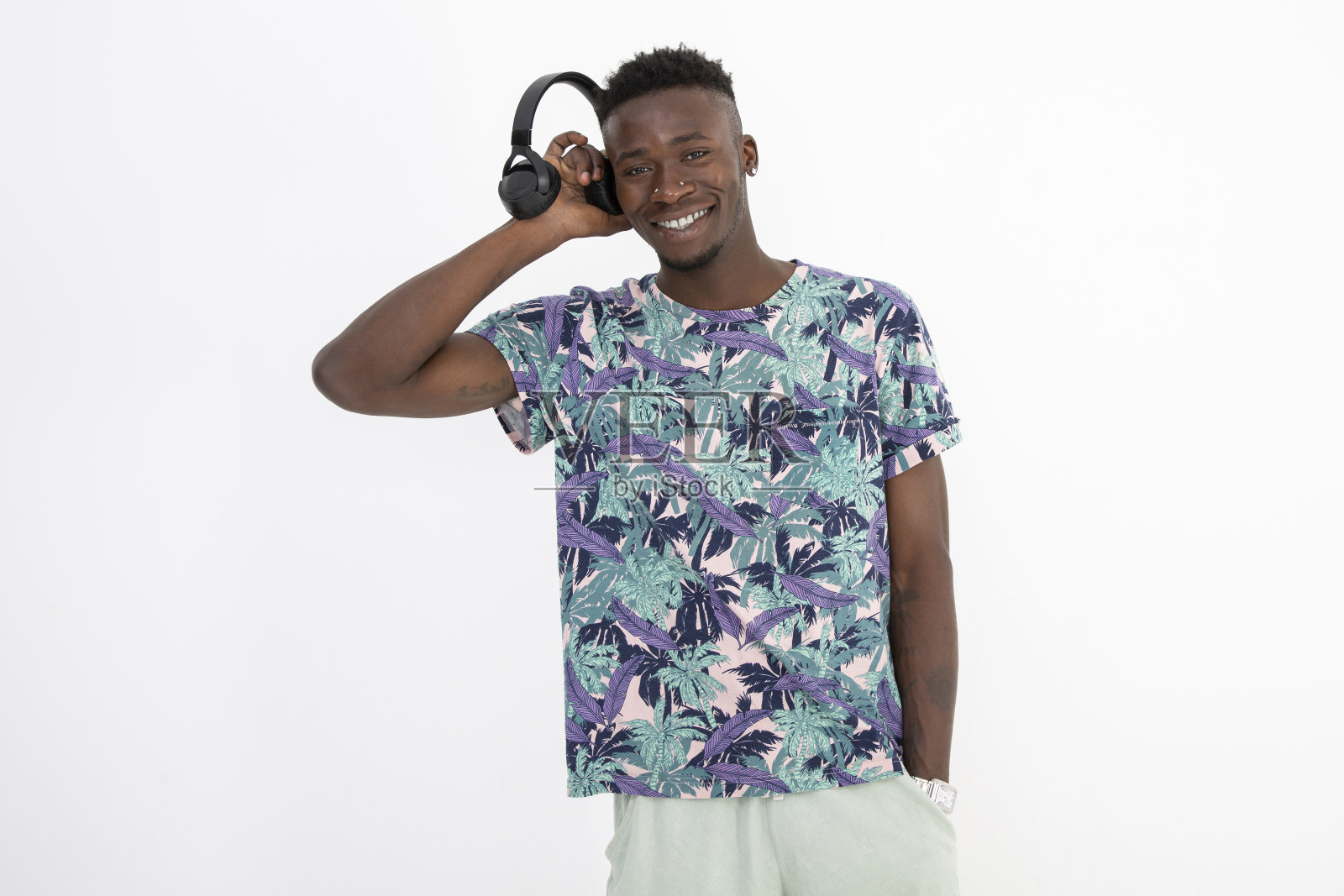 年轻的非洲裔黑人男子穿着有图案的彩色t恤，戴着耳机，做出不同的面部表情。照片摄影图片