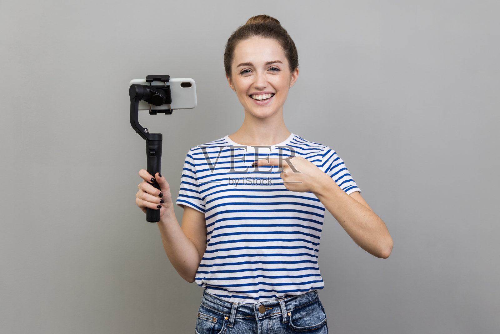 女子手持手机，指着定位仪，表情积极地看着相机。照片摄影图片