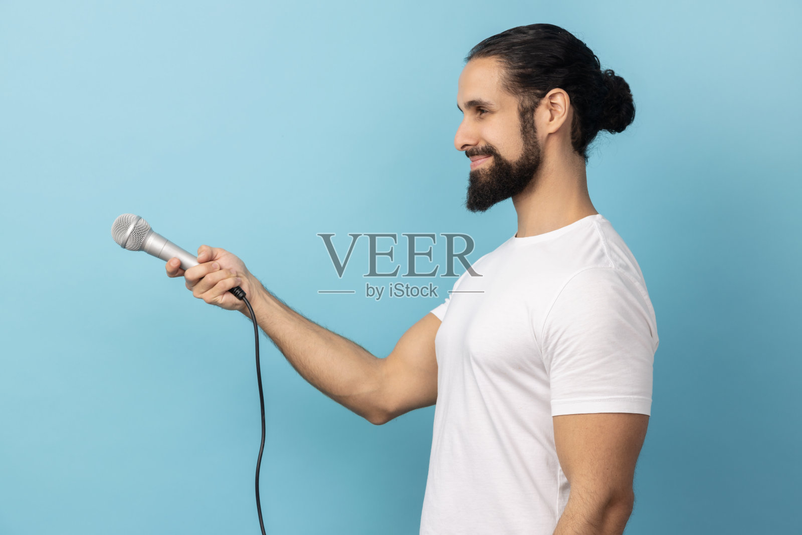 穿着白色T恤的男人拿着麦克风进行采访并征求意见的侧面视角照片摄影图片