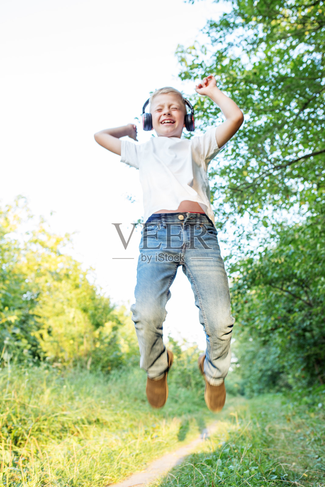 十几岁的男孩听着歌，跳着舞。金发男孩戴着耳机。音乐、广播的概念照片摄影图片