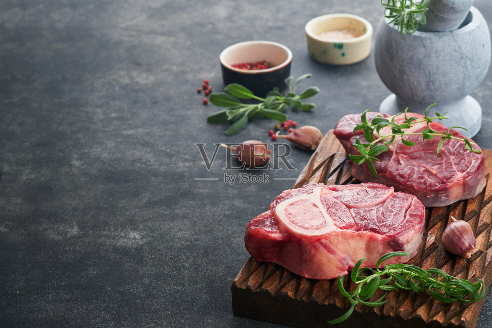 奥索布科生牛排肉。烧烤的肉。新鲜的横切小牛排和调味胡椒，迷迭香，百里香和盐在古老的木制乡村背景。牛腿片配骨髓。意大利菜单。照片摄影图片